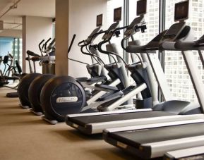 The hotel fitness center is equipped with a range of exercise machines, and large windows with city views.