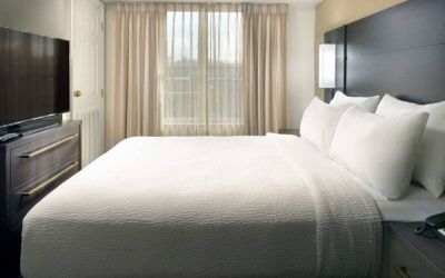 Double bed guest room with a window and large TV at Sonesta ES Suites Raleigh Durham Airport Morrisville.
