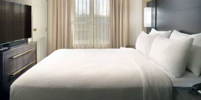 Double bed guest room with a window and large TV at Sonesta ES Suites Raleigh Durham Airport Morrisville.