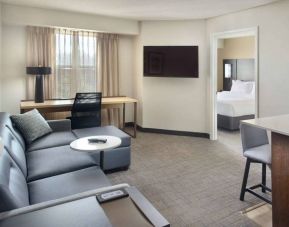 Double bed guest room living area in Sonesta ES Suites Raleigh Durham Airport Morrisville, with sofa, window, and TV.