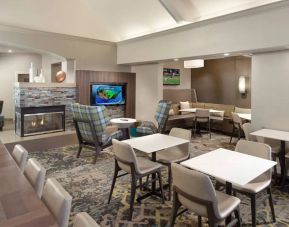 Lobby lounge furnished with sofa seating, tables and chairs, a fireplace and TV, at Sonesta ES Suites Raleigh Durham Airport Morrisville.