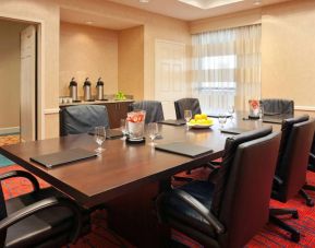 Hotel meeting room with long wooden table, large window, and eight leather chairs.