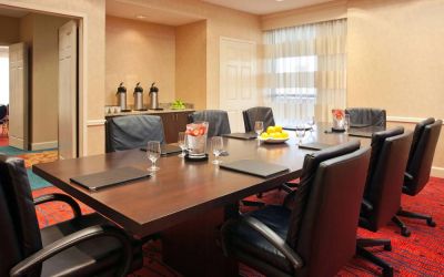 Hotel meeting room with long wooden table, large window, and eight leather chairs.