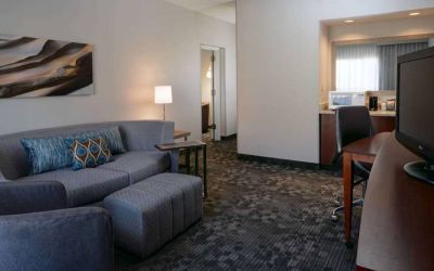 Guest room living area with sofa, chair, and TV at Sonesta Select Kansas City South Overland Park.