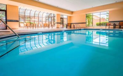 Indoor pool with large windows and tables and chairs at Sonesta Select Kansas City South Overland Park.