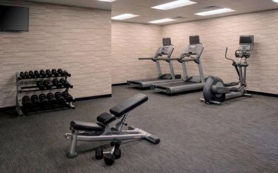 Fitness center furnished with free weights, assorted exercise machines, and a TV at Sonesta Select Kansas City South Overland Park.