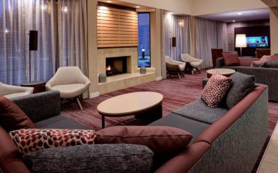 Sonesta Select Kansas City South Overland Park’s lobby lounge features a fireplace and wall-mounted TV, with extensive sofa seating and comfy chairs.