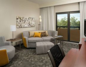 Guest room living area in Sonesta Select Miami Lakes, including sofa, chair, and TV.