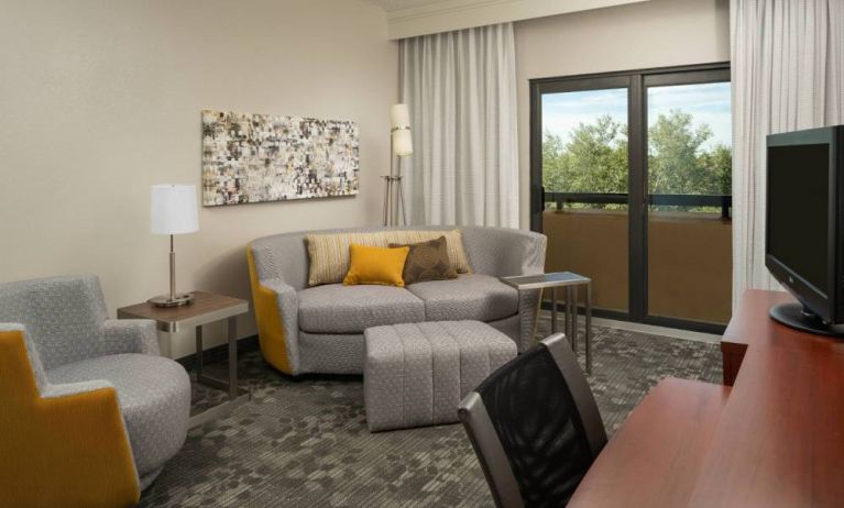 Guest room living area in Sonesta Select Miami Lakes, including sofa, chair, and TV.