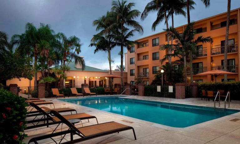 Outdoor pool a mix of sun loungers and shaded tables and chairs by the side, at Sonesta Select Miami Lakes.