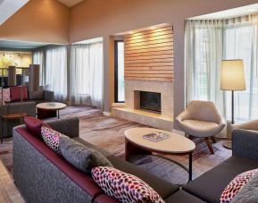 Lounge in the hotel lobby, including large windows, coffee tables, comfy seating, and a fireplace.