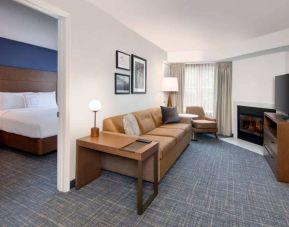 Guest room living area in Sonesta ES Suites Atlanta Alpharetta North Point Mall, with sofa, fireplace,  and TV.