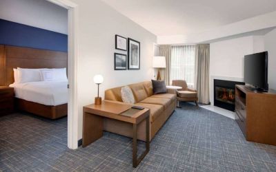 Guest room living area in Sonesta ES Suites Atlanta Alpharetta North Point Mall, with sofa, fireplace,  and TV.