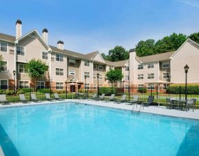 Sonesta ES Suites Atlanta Alpharetta North Point Mall’s outdoor pool has tables and chairs, and sun loungers, by the side.