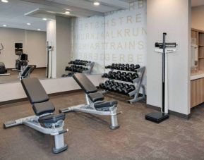 Hotel fitness center equipped with free weights, benches, and various exercise machines.