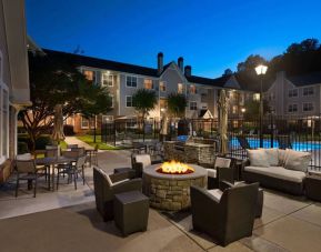 Patio area with fire pit, barbecue, tables and chairs, and armchairs, at Sonesta ES Suites Atlanta Alpharetta North Point Mall.