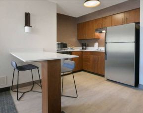 Sonesta ES Suites Fort Worth Fossil Creek guest room kitchen, featuring fridge-freezer, microwave, and table and chairs.