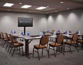 Hotel meeting room, with large table, seating for around 10 attendees, and a large widescreen television.