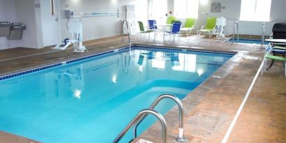 Indoor pool with seating area at Coratel Inn & Suites By Jasper Rochester.