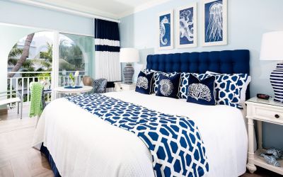 Bright dayroom with white and blue queen size bed and patio view at Oyster Bay Beach Resort.