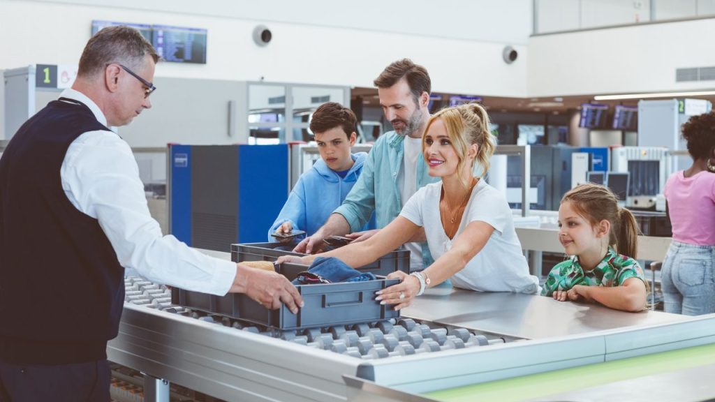 family handing over their belonging to airport security employee