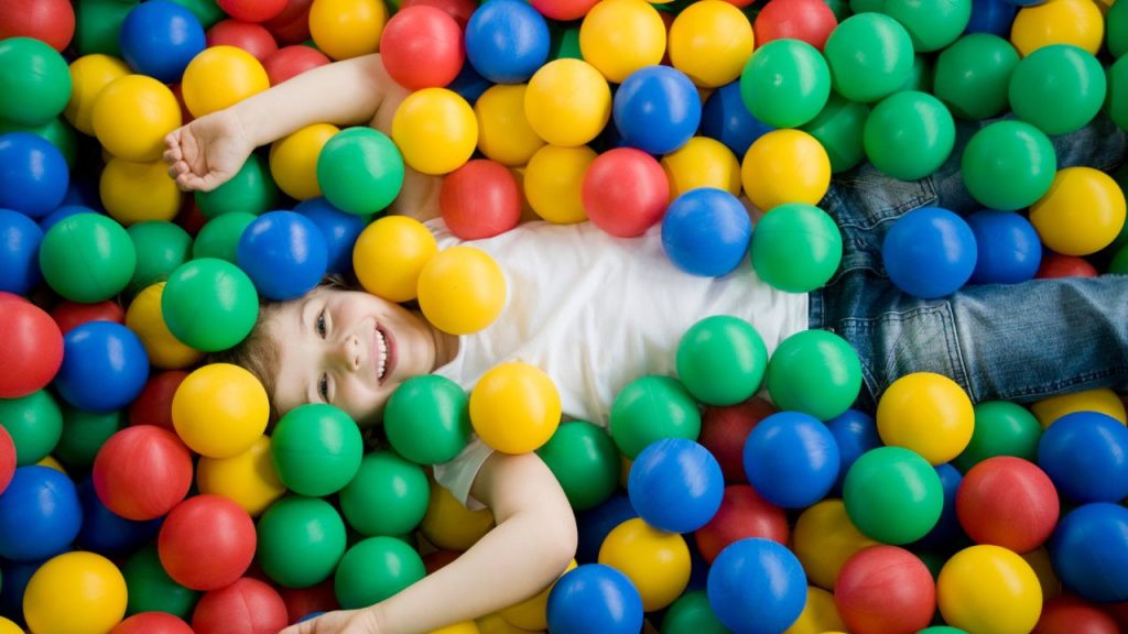 child in fun balls playground: child laying down in recreation area filled with fun ballls