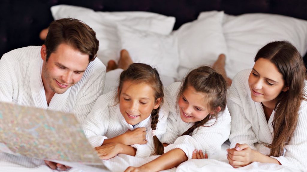 family at day use hotel: man woman and two children relaxing on day use hotel bed in white robes