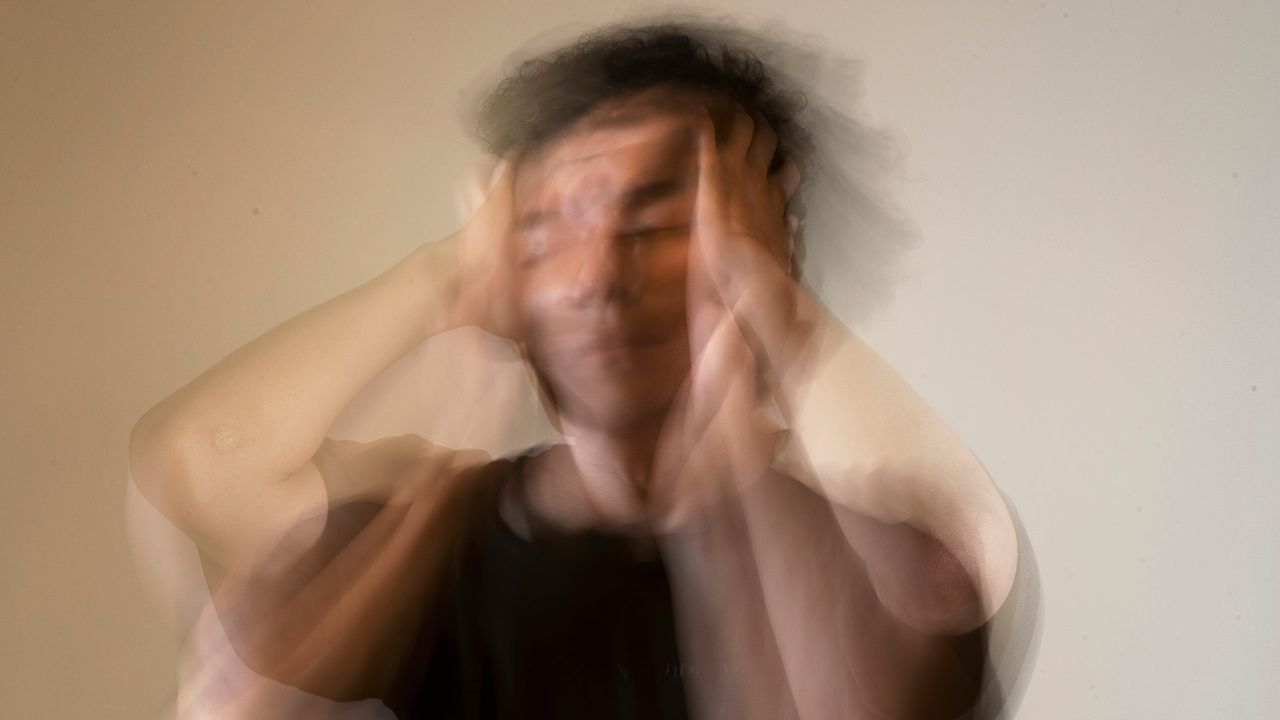 combat stress and sleeplessness with hotelsbyday: blurred image of a man with hands on his head looking stressed