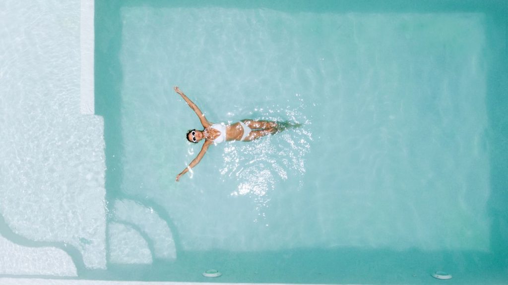solo-daycation-escape: woman floating in resort pool by herself