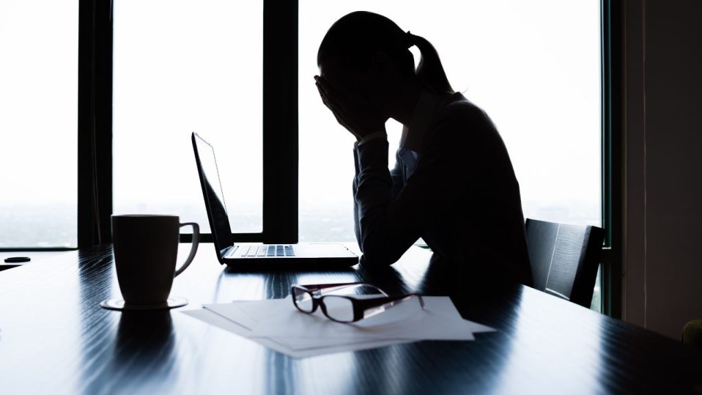 take a workation: lady at office sitting at her desk with head in her hands