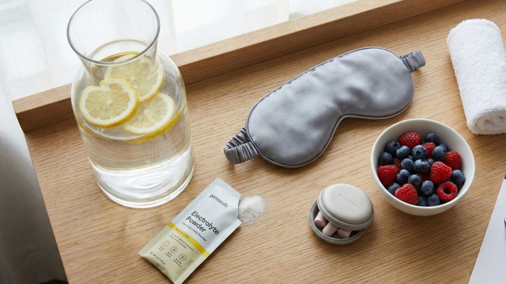 Travel recovery kit including hydration essentials, electrolytes, eye mask, and healthy snacks for a hotel day stay
