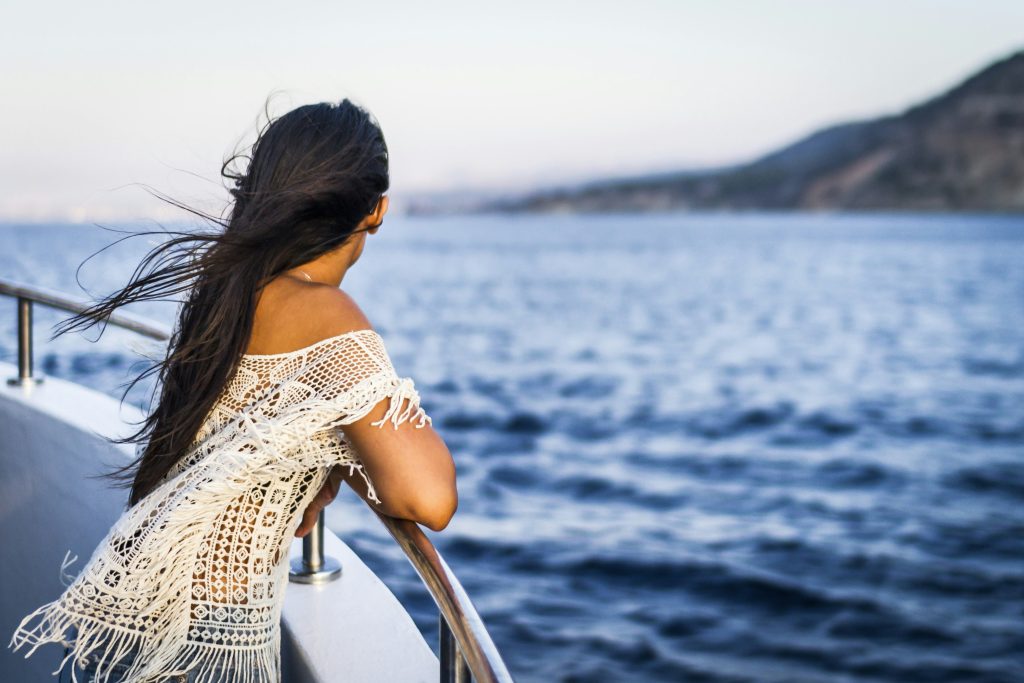 best time to take a cruise: woman overlooks cruise ship bow at ocean