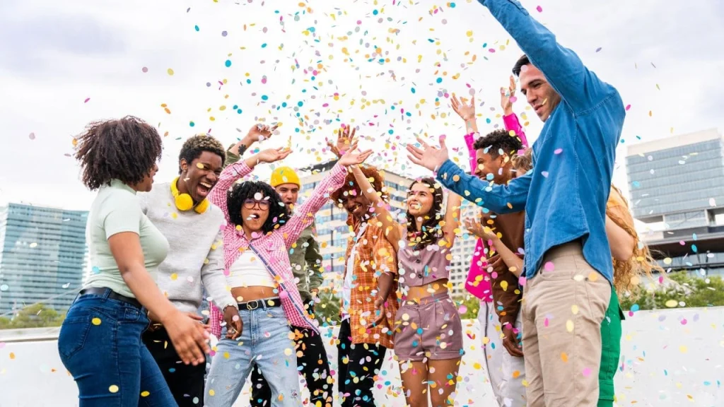 hotelsbyday is one platform for all hotel stays: group of people celebrating in front of hotel with confetti in the air