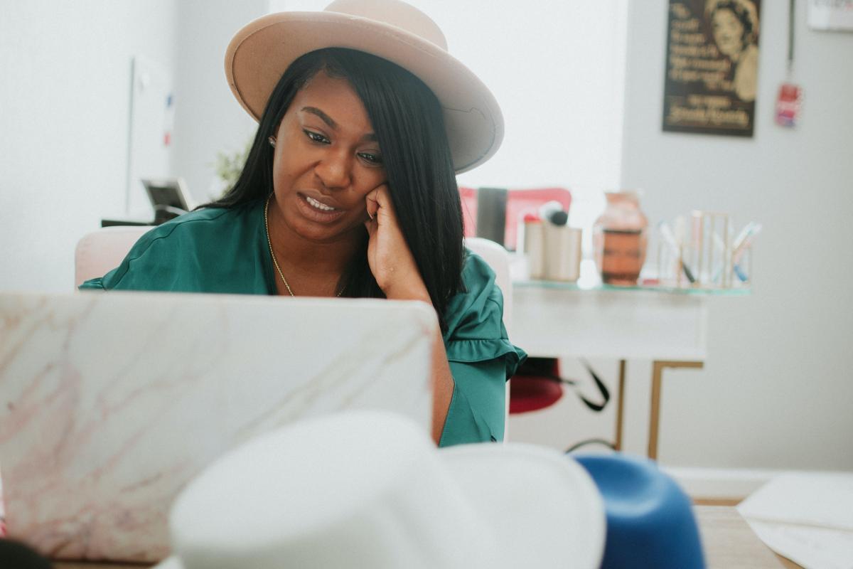 Woman works on laptop while feeling stressed, anxious.