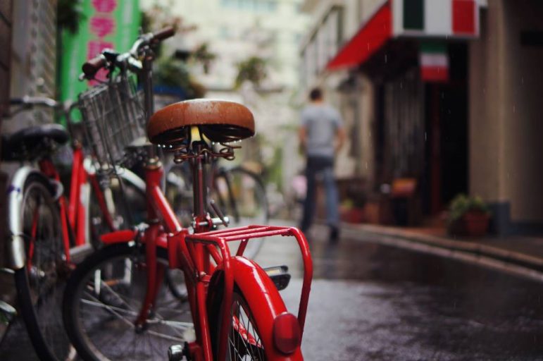 Red bicycle parked in narrow street in urban area.