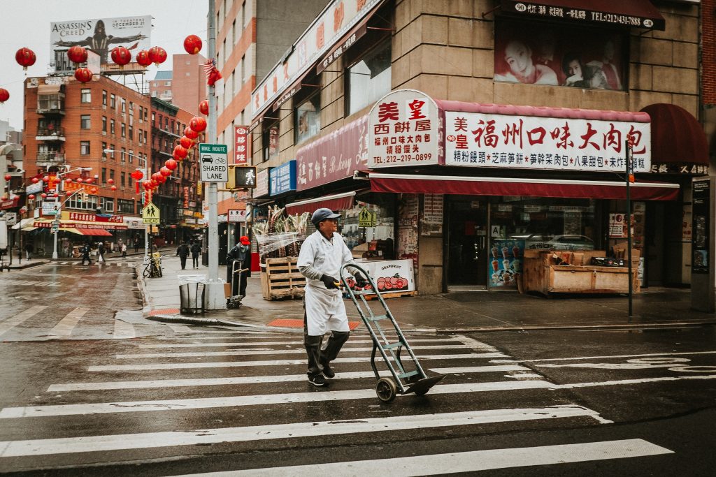 Man pushes dolly on rainy Monday in NYC's Chinatown
