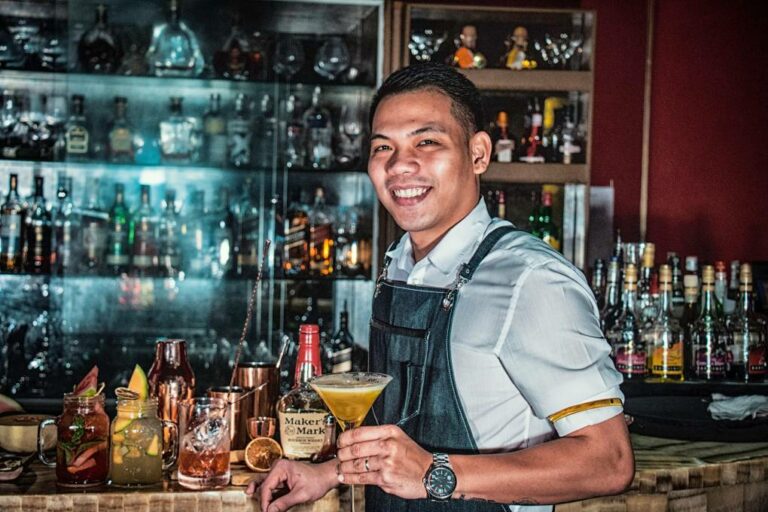Friendly bartender holds a freshly mixed martini cocktail in Doha, Qatar.