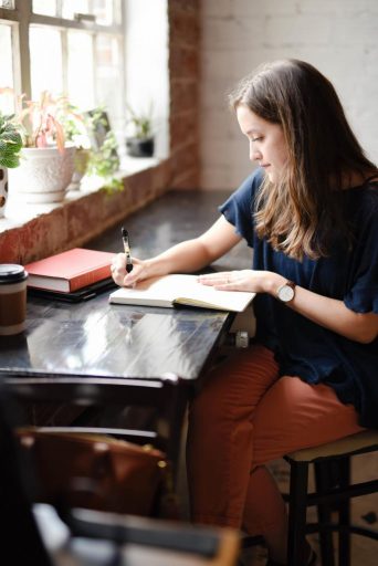 Woman practices gratitude by writing in her journal.