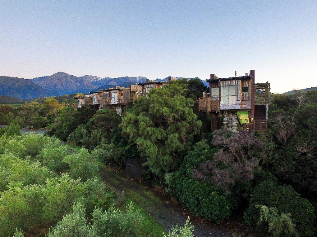 Ecolodge treehouses line a mountain backdrop in New Zealand
