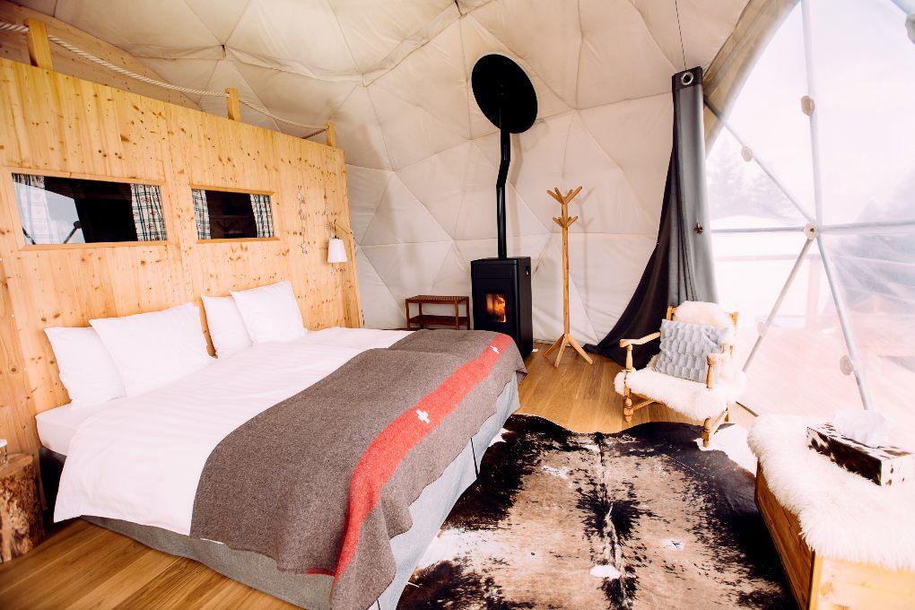 White king size bed with fireplace in white-walled interior dome.