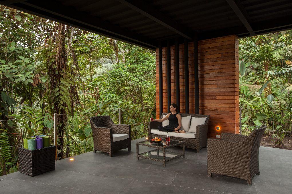 Woman sitting with open-wall view of rainforest.