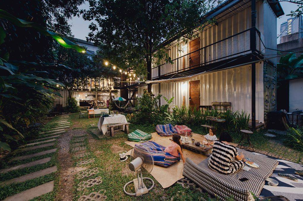 People hanging out in large yard with lights and various seats