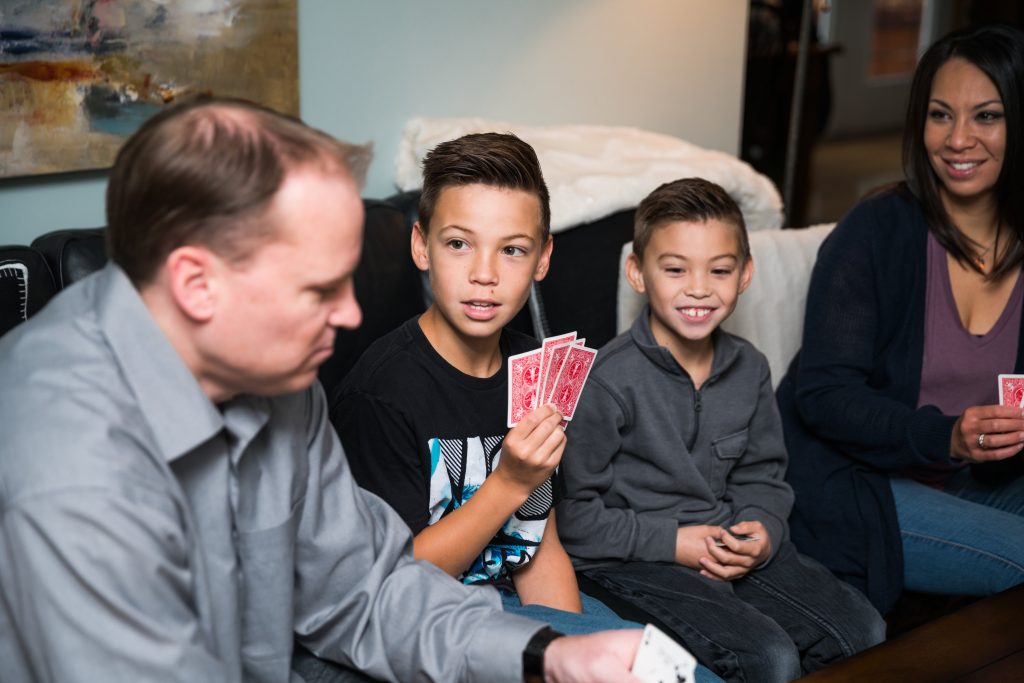 Family sits around playing card games and enjoying each other.