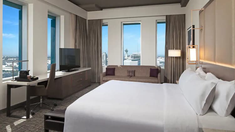 Hotel room with king-size bed, large workstation, television and beautiful city view.