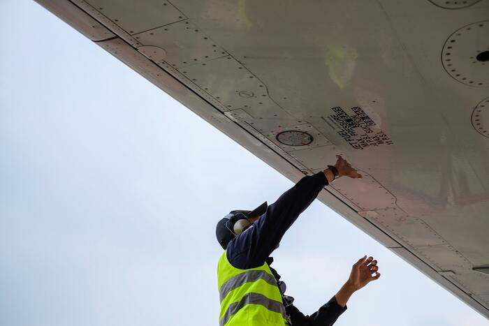 Engineer finishes refueling jet plane, closes fuel hatch.