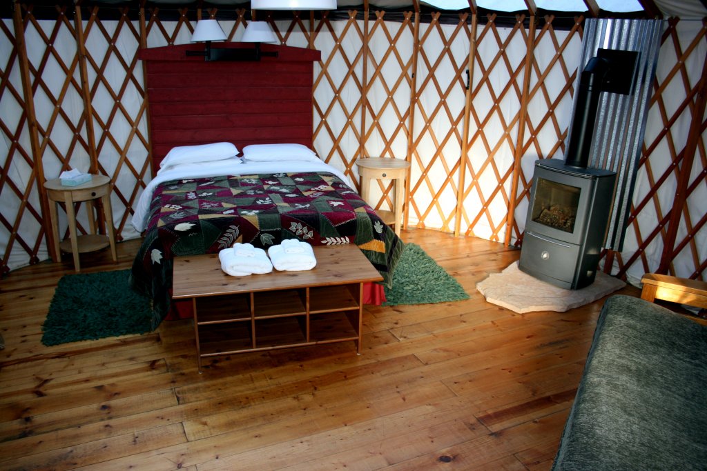 Cozy yurt interior with double bed and fireplace.